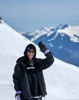 Snowboarder wearing The Team Transform x Glitterstudio Lavender mitten on a snowy mountain.