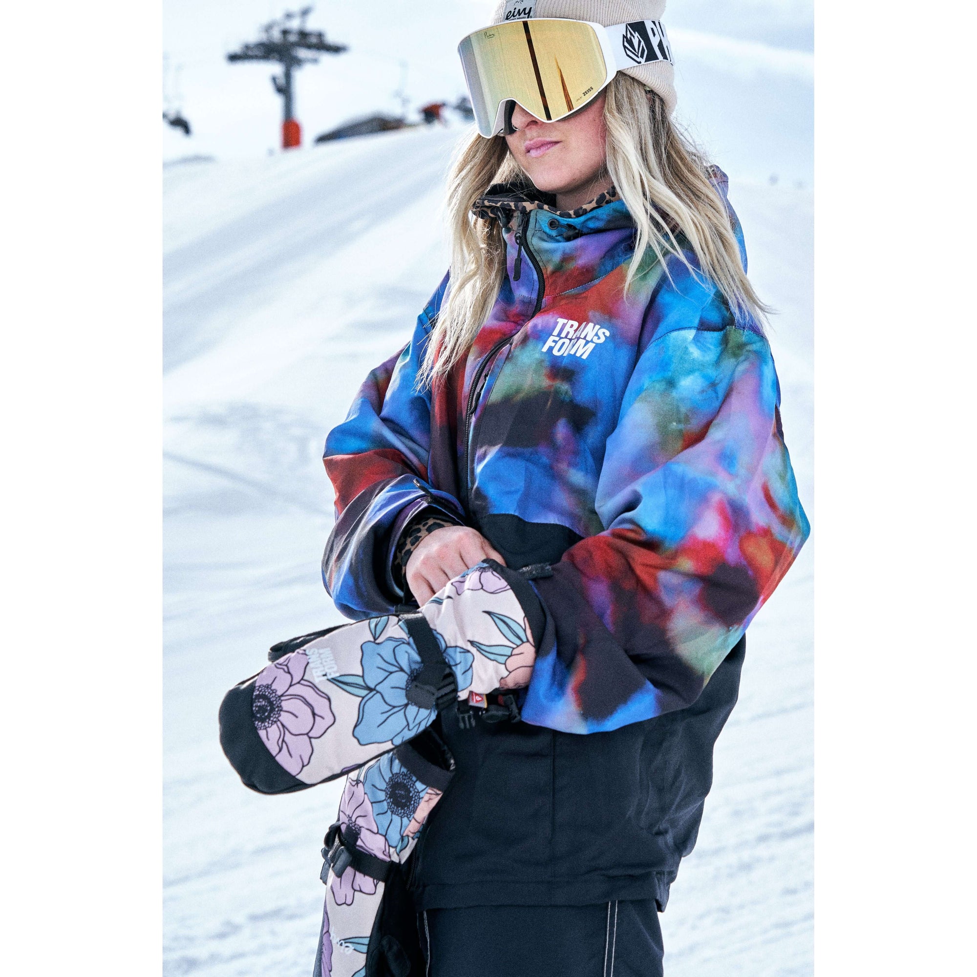 Snowboarder wearing colorful weatherproof jacket and goggles on snowy hill.