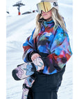 Snowboarder wearing colorful weatherproof jacket and goggles on snowy hill.