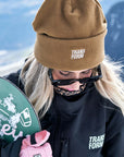 Snowboarder wearing Transform gear and holding a snowboard with pink Photo Incentive Gloves.