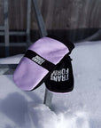 Pink and black snowboard mittens on snowy rail, perfect for spring snowboarding activities.