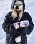 Person snowboarding in winter gear featuring The Team Transform x Eivy Big Flower mittens with Primaloft insulation and waterproof inserts.